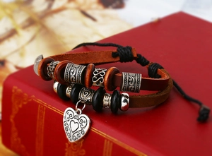 Détail macro du bracelet en cuir bohème avec perles en bois et breloque cœur gravé