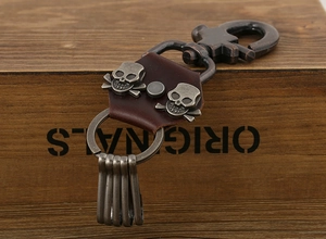 Punk leather skull keychain with antique bronze hooks on a vintage wood background