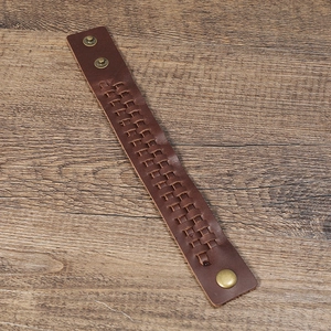 Bracelet en cuir tressé marron rétro avec clous en métal sur fond de bois sombre