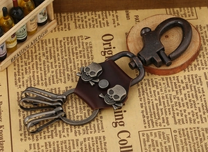 Detail of vintage leather keychain with 3D skull rivets and horseshoe clasp on retro background