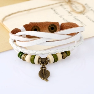 Detailed macro shot of vintage multilayer white leather bracelet with bronze leaf pendant
