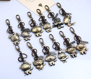 Detailed collection of twelve retro bronze zodiac keychains on light blue backdrop