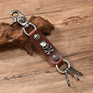 Detail of punk skull genuine leather keychain with vintage silver alloy hooks on wood