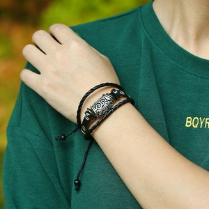 Close-up of a woven leather bracelet featuring a silver metal cylinder with vintage relief