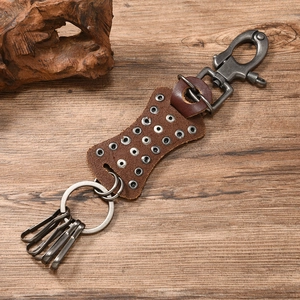 Detail of vintage brown leather keychain with star rivets and metal spring hooks on wood