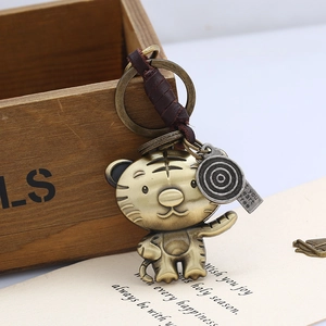 Close-up of vintage bronze tiger keychain with brown leather strap and engraved charms