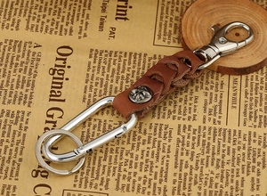 Macro detail of brown braided leather keychain with vintage silver cross snap button