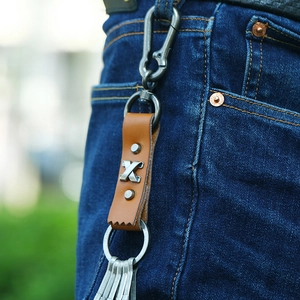 Vintage brown leather keychain with metal accents clipped to a denim belt loop