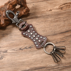Macro detail of dark brown leather keychain with silver star rivets on wood background