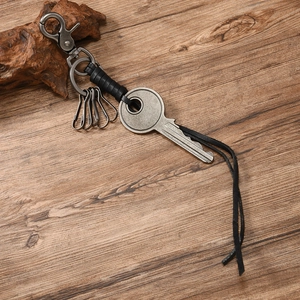 Macro shot of retro metal key pendant with black leather strap on dark wood