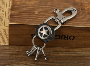 Detail of vintage silver star alloy keychain with black leather accent on retro wood box