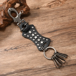 Detail of punk leather keychain with star studs and lobster clasp on wood surface