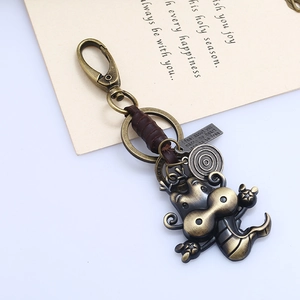 Close-up of vintage bronze dragon keychain with leather strap and engraved metal tag
