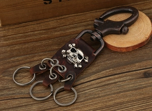 Detail of a vintage punk leather keychain with metal skull motifs and rotating spring hook