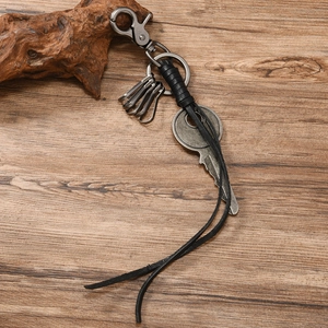 Detail view of retro braided leather keychain with vintage metal key pendant on wood