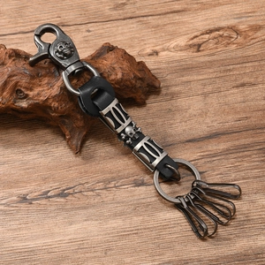 Detail of punk style skull keychain with black leather and antique alloy hooks on wood