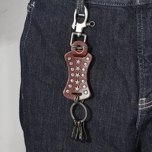 Punk style brown leather keychain with metal rivets and star studs on denim background