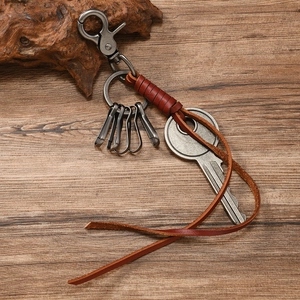 Detail of vintage hand-woven leather keychain with antique silver metal clips and key