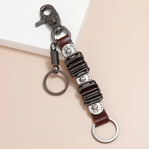 Vintage punk skull keychain with dark brown leather strap and embossed silver alloy discs