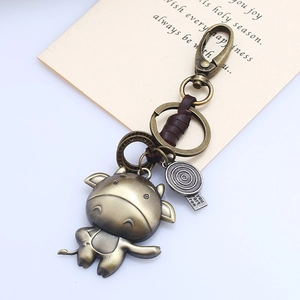 Detail of vintage bronze zodiac ox keychain with dark brown leather and engraved charms