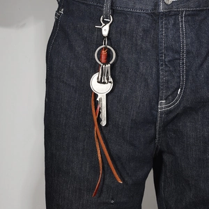 Handmade leather keychain with metal carabiner and tassels on denim pants