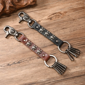Punk style leather keychain with skull studs and silver hardware on a wooden background