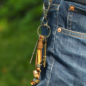 Vintage braided brown leather keychain with bronze key charms on dark denim jeans