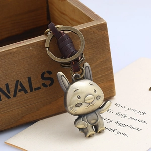 Detail of vintage bronze rabbit keychain with dark brown leather wrap on wood background