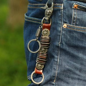 Retro leather keychain with skull charms and metal hook shown on denim pants