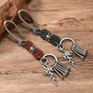 Punk style leather keychain set with skull and cross charms on vintage wood surface