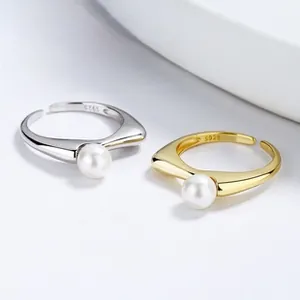 Detailed view of polished S925 silver and gold open rings with white freshwater pearls