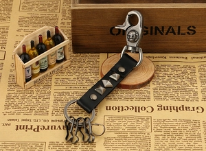 Detail view of punk leather keychain with silver rivets and skull buckle on vintage background