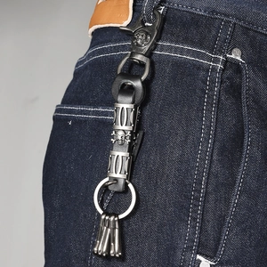 Punk style skull keychain with leather strap and metal hook on denim jeans