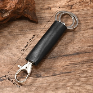 Porte-clés artisanal en cuir noir avec mousqueton en argent sur fond en bois rustique