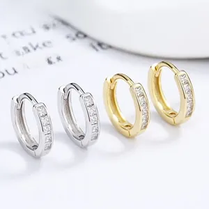 Macro view of sterling silver and gold huggie earrings with channel-set square zircons