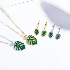 Detail of green enamel monstera leaf jewelry set with gold and silver necklaces