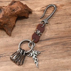 Detail of vintage U-hook leather keychain with skull motif and flame cross pendant
