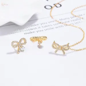 Macro detail of gold bow jewelry set with sparkling zircons on a white plate