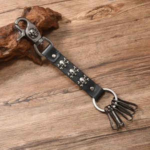 Detail of punk leather skull keychain with silver buckles on a rustic wood surface