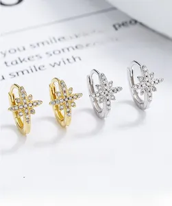 Detailed view of silver and gold eight-pointed star hoop earrings with cubic zirconia