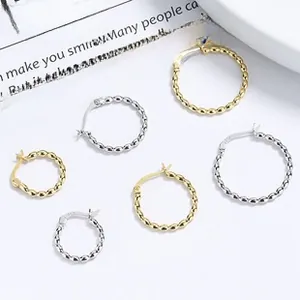 Macro shot of 925 sterling silver hoop earrings with twisted rope texture in gold and silver