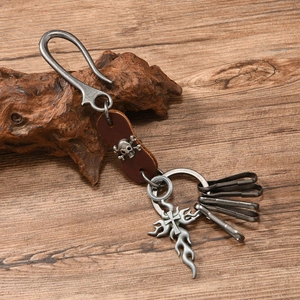 Detailed macro view of vintage leather keychain with silver skull and flame cross pendant