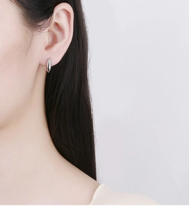 Close-up of minimalist S925 sterling silver leaf earrings worn by a model in soft light