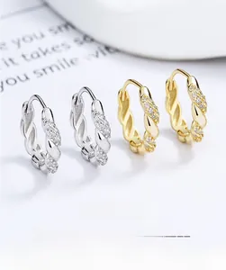 Close-up of twist hoop earrings in gold and silver finish with pavé set zircon stones