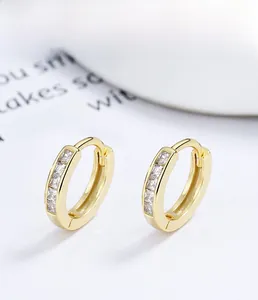 Détail macro de créoles en argent S925 doré avec pavé de zircons carrés scintillants