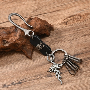 Close-up of punk leather keychain with skull element and flame cross on driftwood
