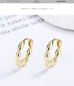 Close-up of golden S925 sterling silver twist hoop earrings with wavy texture finish