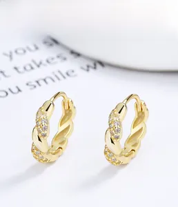 Detailed macro view of S925 sterling silver gold twisted hoop earrings with pavé crystals