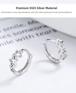 Gros plan de créoles en argent sterling 925 avec étoiles évidées sur surface blanche