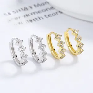 Macro detail of geometric silver and gold earrings with pavé cubic zirconia settings